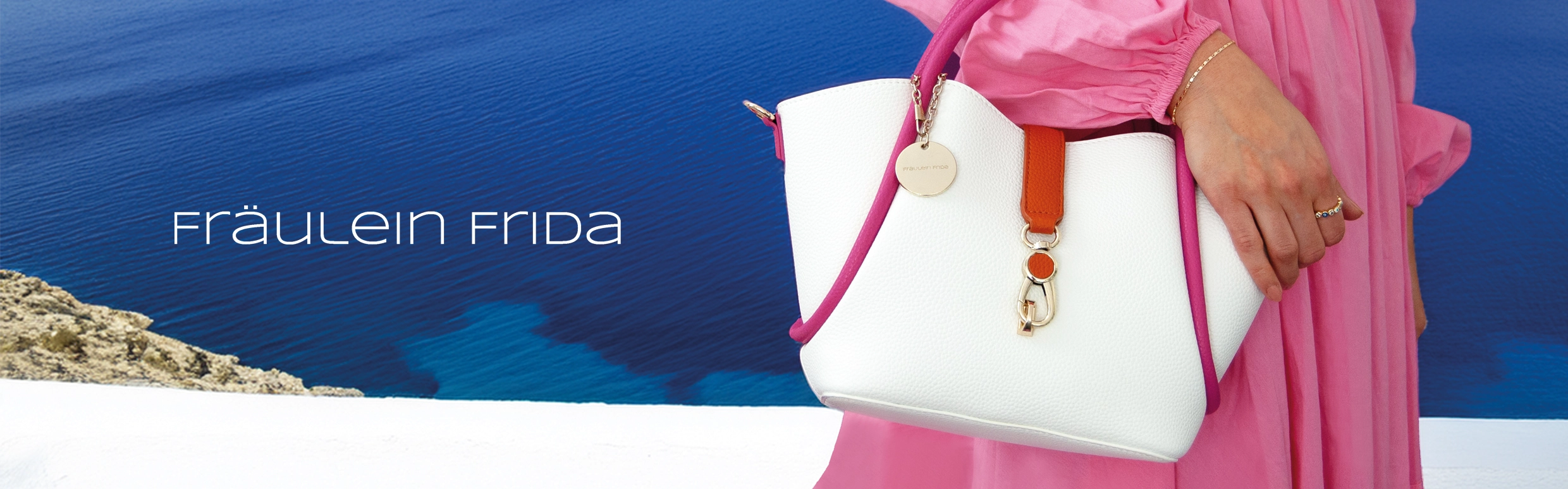 Eine Frau mit einer Fräulein Frida Handtasche im Hintergrund ist das Meer zu sehen