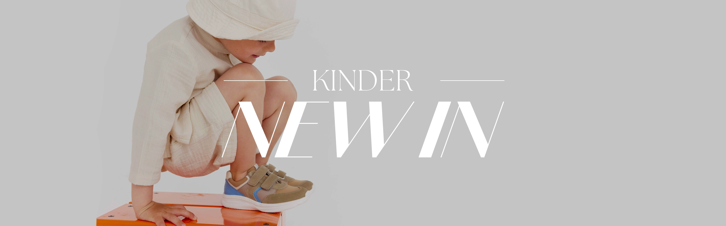 Schriftzug NEW IN im Hintergrund ein Kind das Sneaker trägt