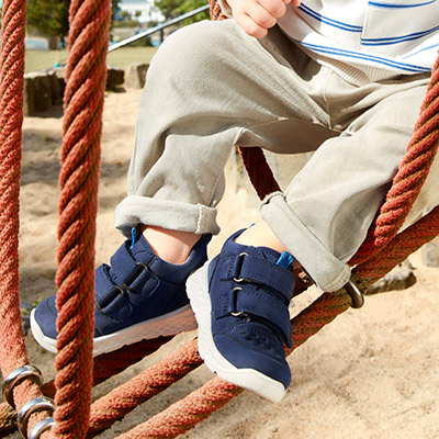 Kind mit blauen WMS Schuhen auf dem Spielplatz